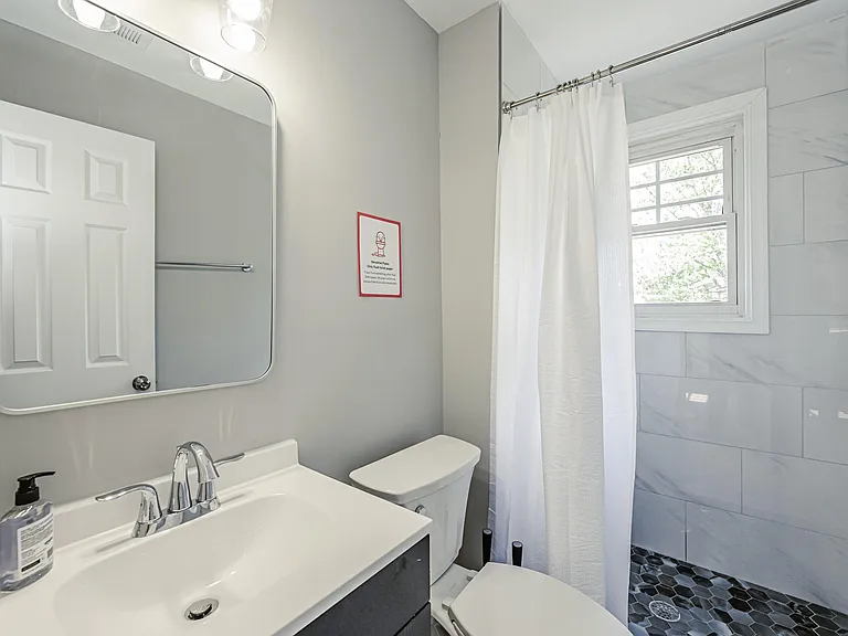Updated full bath with tiled tub/shower surround, vanity storage, and a window for ventilation and natural light.
