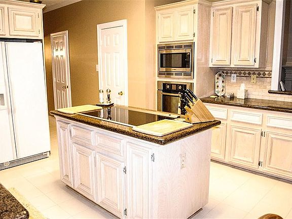  Now this is a kitchen you can cook in! Granite countertops, tile backsplash, tile floor, island cooktop, open to the family and breakfast area.