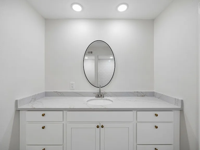 Bathroom vanity featuring a white countertop with subtle veining, undermount sink, and brushed nickel faucet