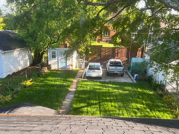 View of backyard where there is room for two vehicles, a custom build 8x10 shed, and a raised carden bed where you can plant what you would like to grow.