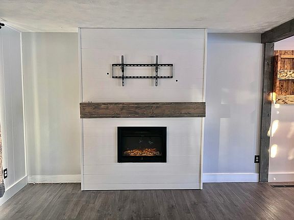 Living room featuring electric fireplace with wooden mantle