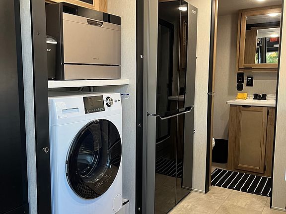 View of the other side of the kitchen, washer dryer combo, dishwasher, ice maker and full size refrigerator.