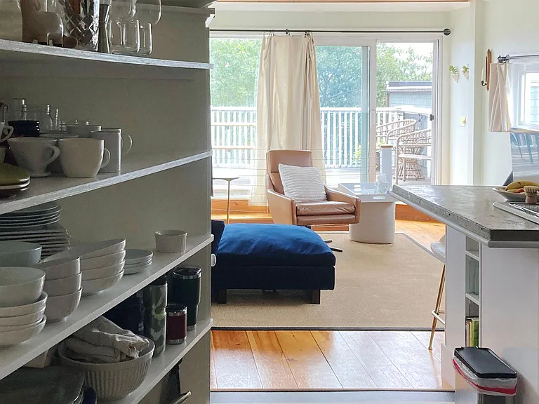Open shelving in kitchen, view toward living area and private deck.