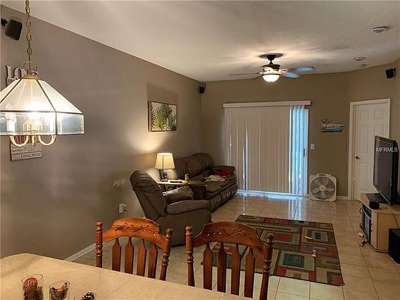 Great room view looking towards the sliding glass doors with blinds leading to Screen Porch showing ceiling fan lights tile floo