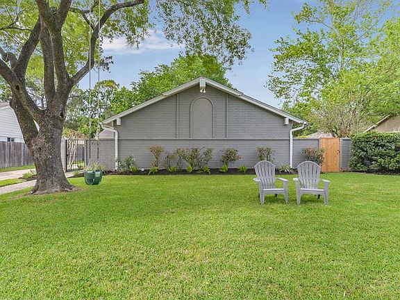 ANOTHER VIEW OF THE FRONT OF THE HOUSE WITH A LOVEY TREE AND LUSH LAWN