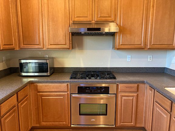 Kitchen with stainless steel appliances: vent, microwave, gas stove, countertop oven, dishwasher, and refrigerator