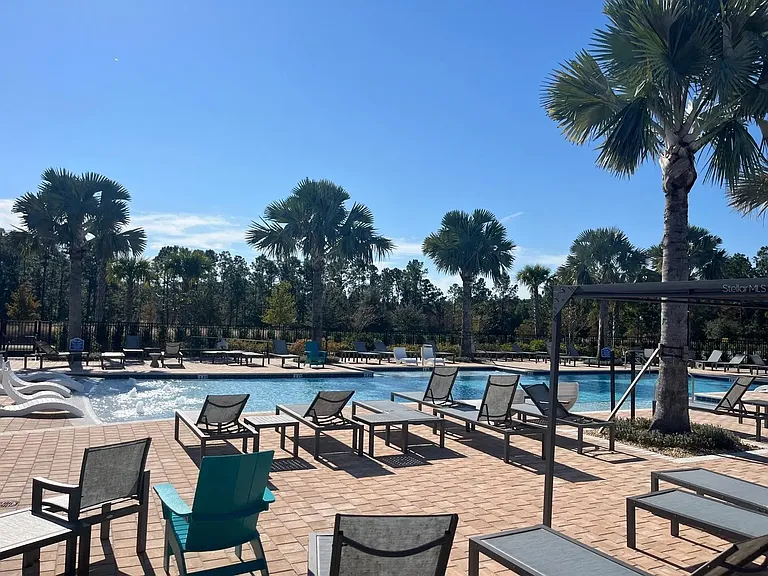 Resort-style community pool with lounge seating, palm landscaping, and sun deck for relaxation and outdoor enjoyment.