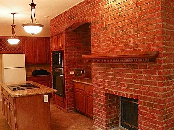 Country kitchen has cozy two sided fireplace to family room
