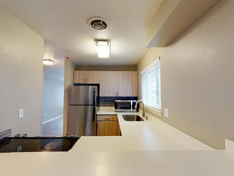 Apartment kitchen with stainless steel appliances, quartz countertops and wood-style flooring.