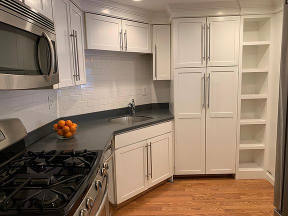 Modern kitchen (11'x9') with Corian counters, tile backsplash and stainless appliances (gas range with oven, microwave, dish-washer and refrigerator)