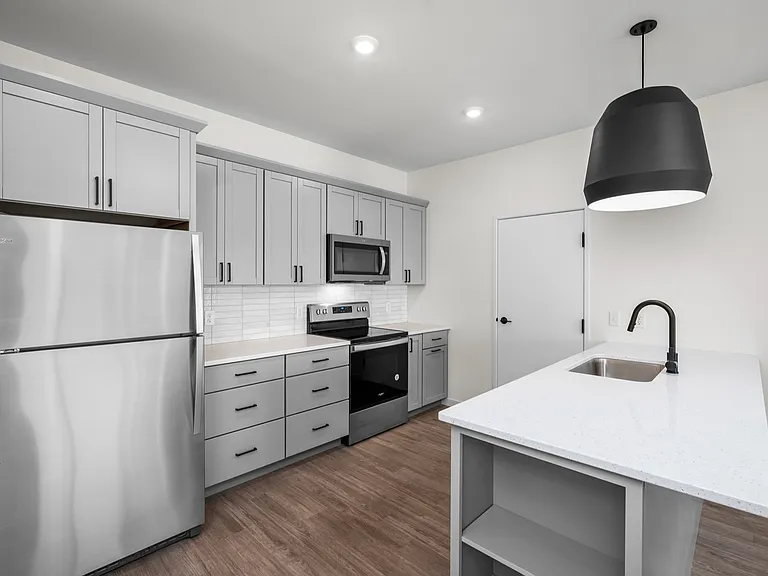 Modern kitchen with sleek grey cabinets, stainless steel appliances, and a stylish pendant light over a spacious island. Modern kitchen with sleek grey cabinets, stainless steel appliances, and a stylish pendant light over a spacious island.