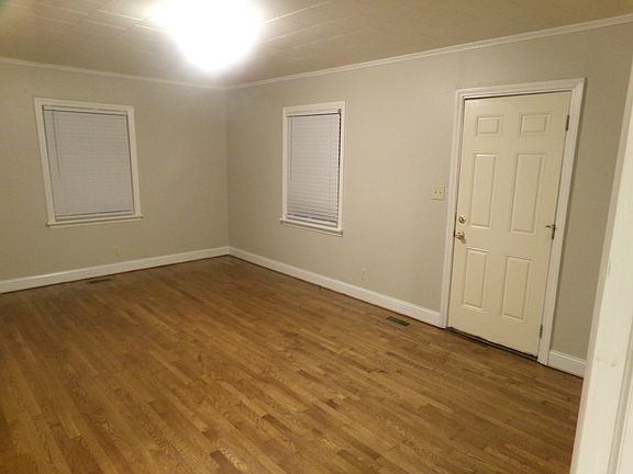 View of the entrance (exterior door featured) to the Living Room. Hardwoods are newly-refinished with new blinds and fresh paint throughout the unit.