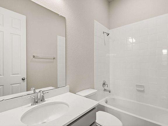 The private bath features a vanity with a shower tub combo
