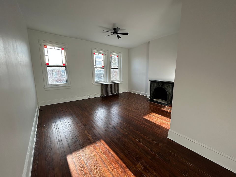 Living room drenched in afternoon sunlight. Windows with stained glass accents. Historic fireplace.