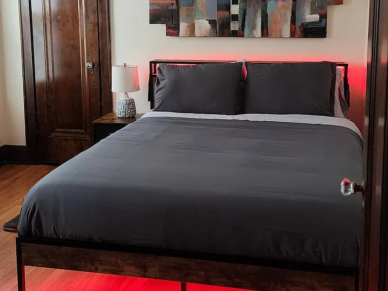 Third Bedroom with new queen-sized bamboo/charcoal/green tea memory foam bed that includes LED lights and a charging station, desk, chair, file cabinet, shelf unit, two rugs, artwork, and large closet with mirror.