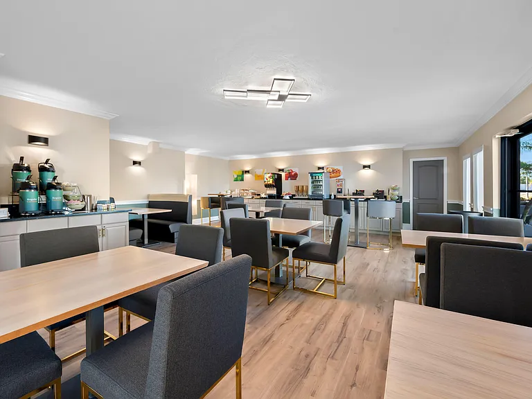 Spacious dining area with multiple tables, booth seating, and a convenient beverage/coffee station for residents.