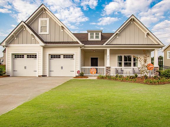 a large white house with a porch and two garages .
