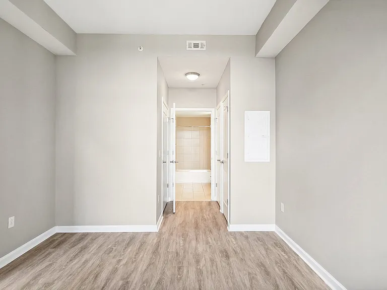 an empty bedroom with white walls and wood flooring