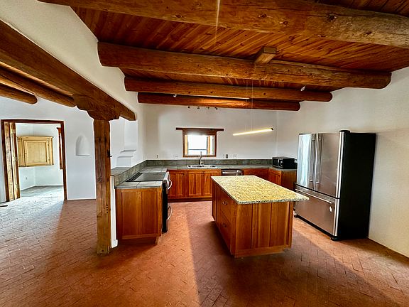 Kitchen with stone and tile countertops with vigas throughout the house