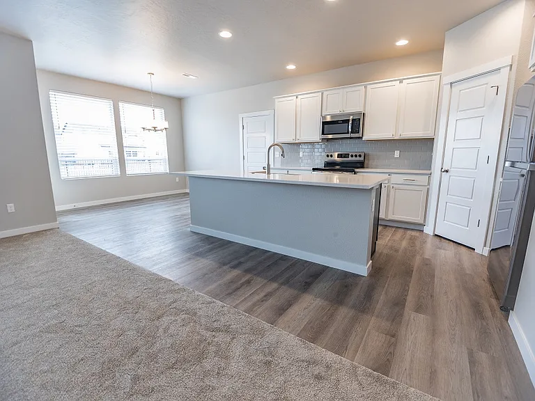 Spacious kitchen with center island, stainless appliances, pantry and dining area.