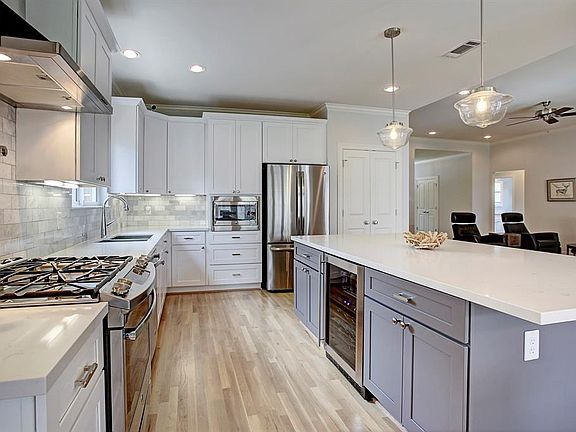 This contemporary kitchen is bright and airy with quartz counters and custom backsplash, stainless appliances, under-counter lighting, wine refrigerator and tons of storage!