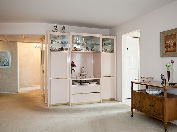 In the large living room is an alcove that offers storage with drawers and shelves to display your b