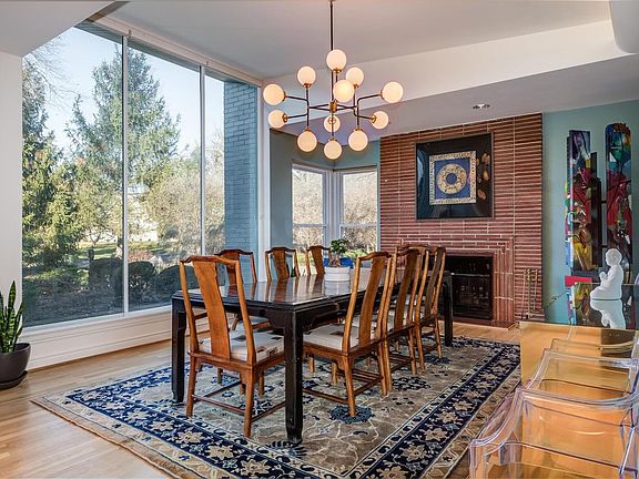 Wall of windows, floor-to-ceiling brick fireplace surround, vaulted ceiling with cove lighting and custom chandelier combine to create an impressive room