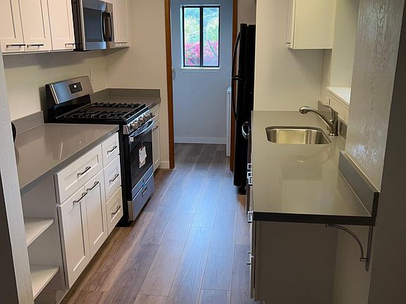 Newly remodeled Kitchen with brand new cabinets, countertops, sink, refrigerator, dishwasher, gas oven/stove and garbage disposal. Washer/Dryer in room behind kitchen (where window is)