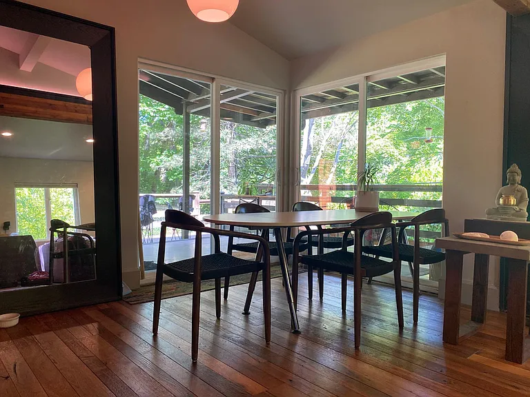 Dining area with double patio doors opens on large covered wrap around porch with views of woods and bird feeders.
