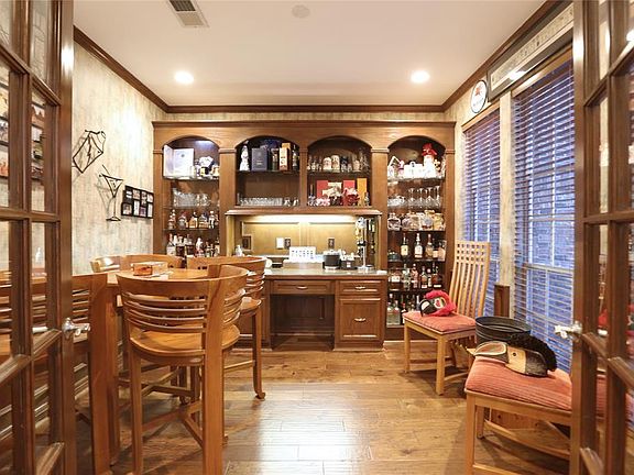 The study is currently in use as a bar, and easily converts back to it's original use. Blinds and wood trim accent the room.