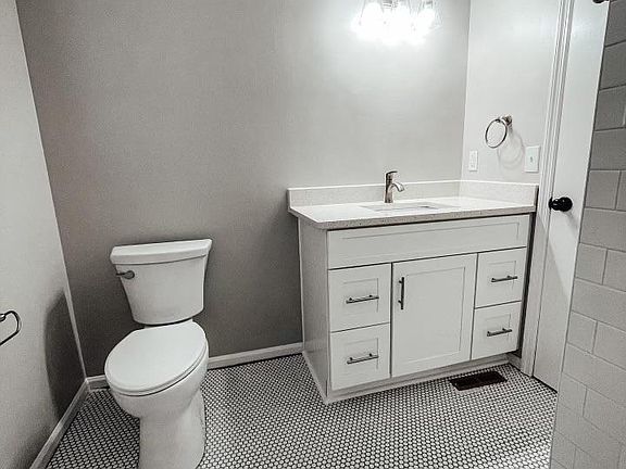Full bathroom with tile floors and quartz countertops.