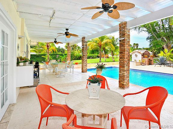 A comfortable cool patio are adjacent to a beautiful pool and yard.