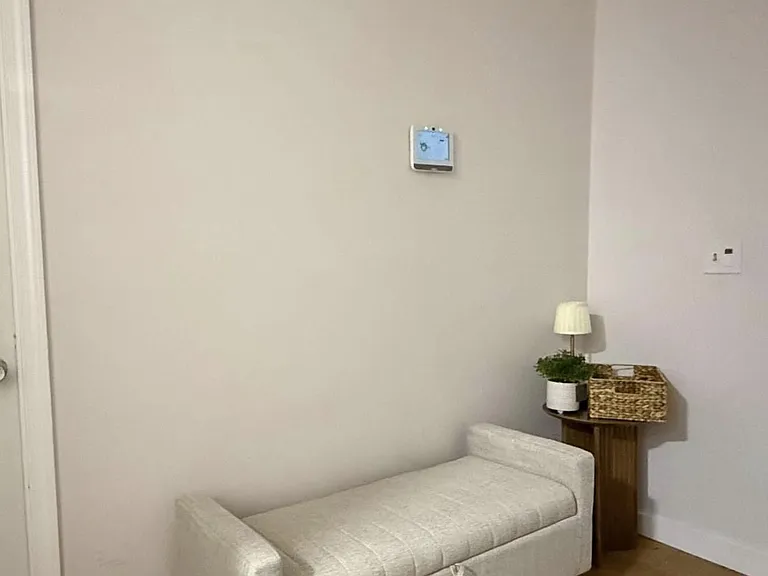 Common sitting area with a lounge bench, side table, and thermostat accessideal as a small waiting or reading nook.