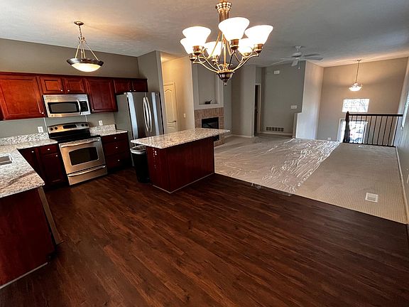 Dining room and kitchen with brand-new flooring and chandelier.