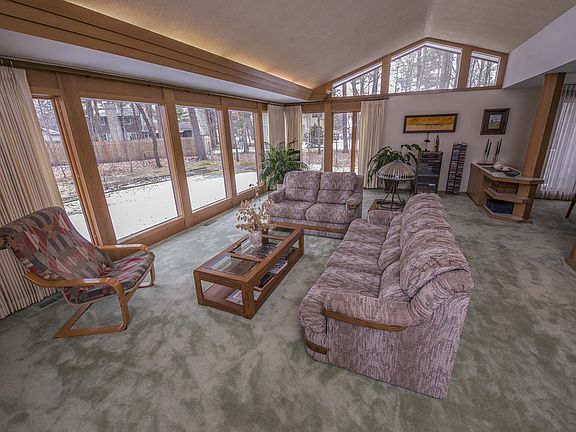 Open concept living room (17x30) features vaulted ceilings, floor to ceiling Anderson windows with original trim, brick mantle and wood-burning fireplace.