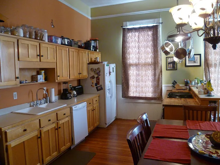 Large, open kitchen with lots of natural lighting, a hanging pot rack, and butcher block countertop.