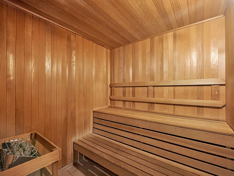 Building sauna with wood benches and traditional sauna heater.