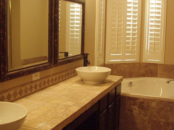 Master Bath with Vessel Sinks, Jetted Tub, Travertine, and Stone.