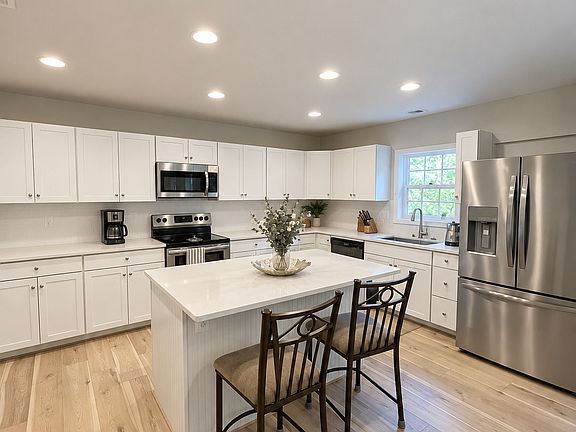 Kitchen island with seating, white cabinetry, and stainless steel appliances.