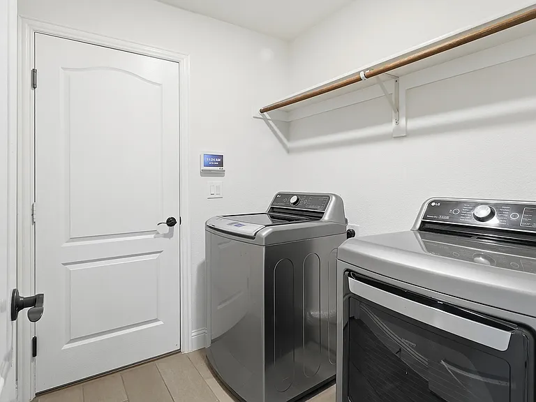Laundry area with wood-finish flooring, white walls, and a built-in shelving unit with a hanging rod