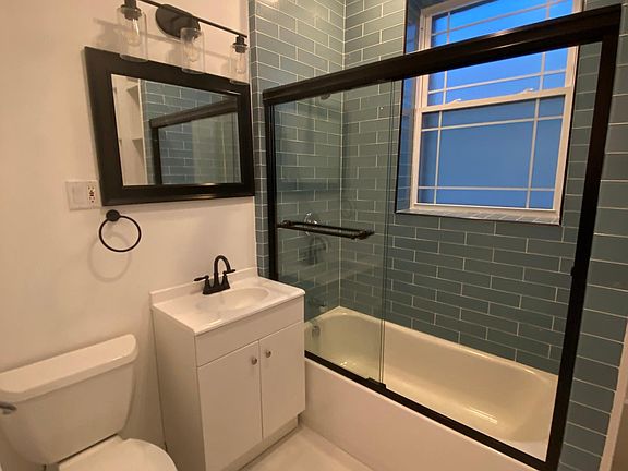 Bathroom with new tile, new toilet, new vanity, and built-in cabinet for towels and products