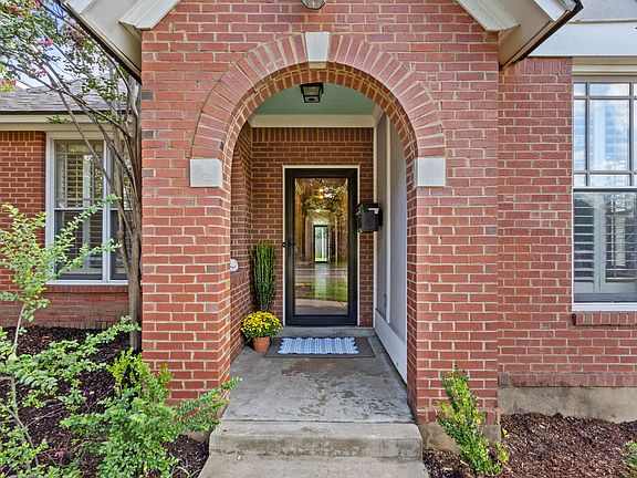 Covered entry with a security door. The long entrance hall opens into the living room. The back door is visible at the end of the hall.