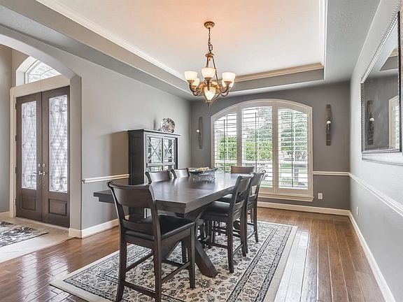 Elegant Formal Dining room with gleaming wood floors, custom chandelier, and plantation shutters