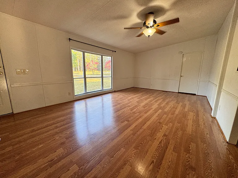 Bright, oversized living room featuring hardwood floors, a large bay window overlooking the front yard, and direct access to the front porch. Plenty of space for family gatherings and everyday living.