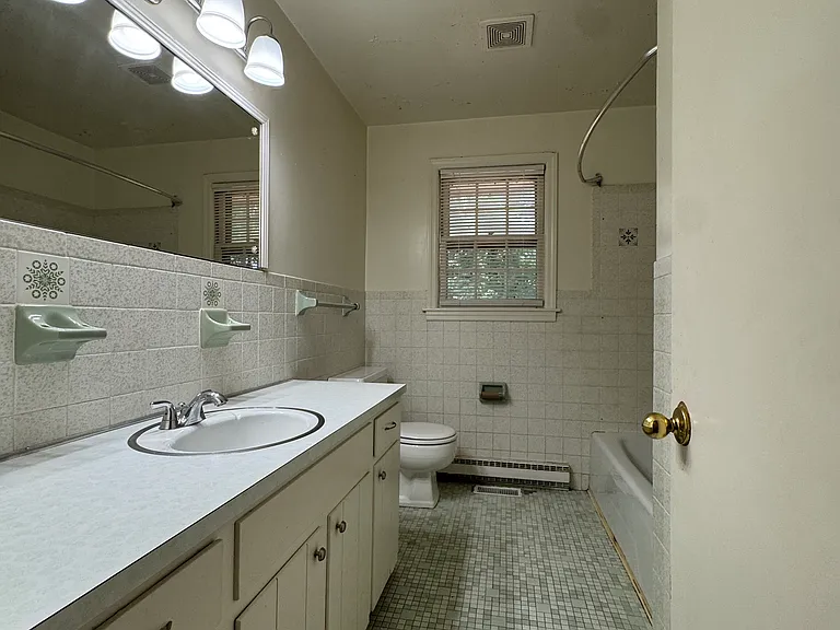 Hall bath with linen closet and tub-shower combo. Window overlooks back yard.