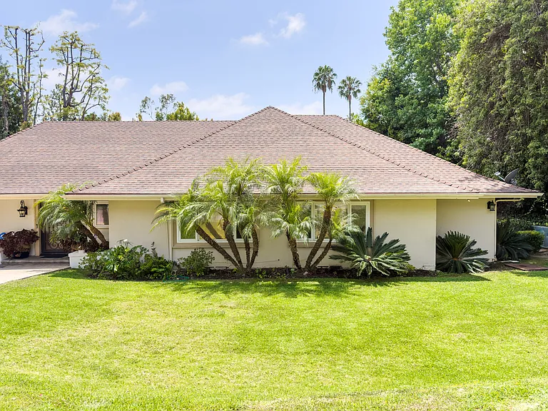 Manicured lawn and mature palms create inviting curb appeal at this Beverly Hills luxury rental home, 1094 Garden Lane, 90210.