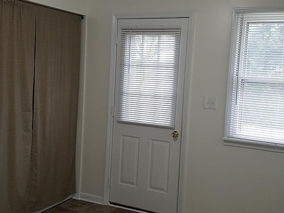 View from kitchen entry, new flooring, washer/dryer concealed behind curtains to the left. Backdoor leads to a small back patio with small yard area.