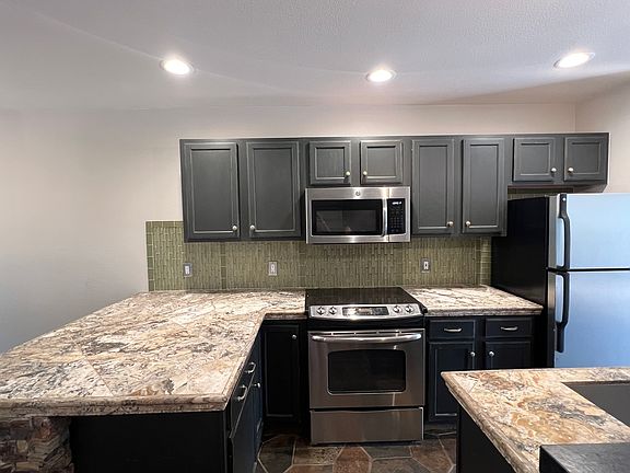 clean kitchen with stainless appliances. Slate flooring in kitchen, hardwood throughout rest of home.