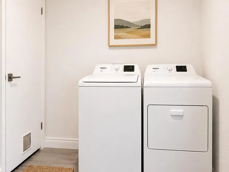 Dedicated laundry area with side-by-side washer and dryer, durable flooring, and easy-access layout off the hallway.
