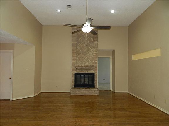 Large family room with wood flooring, high ceiling, and soaring brick fireplace.